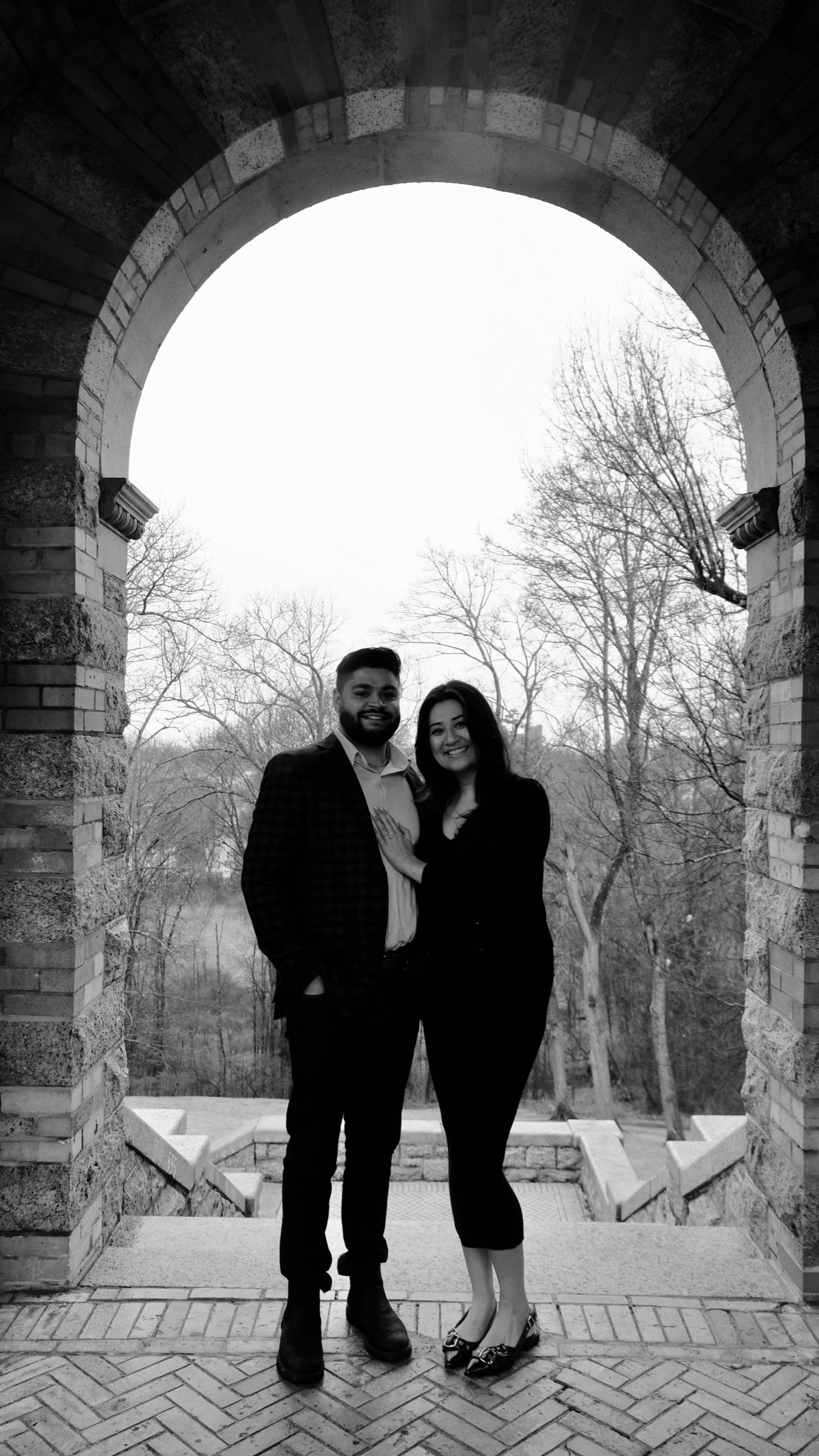 Rohit and Ayushka standing beneath a tall stone arch